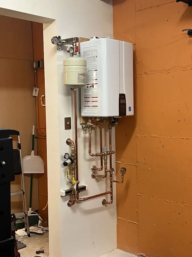 Plumbing technician inspecting water heater connections in Tipton